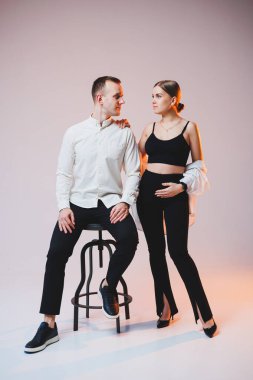 Young couple in love in white shirts hugging on a white background. A happy married couple looks lovingly into each other's eyes. The concept of healthy family relationships