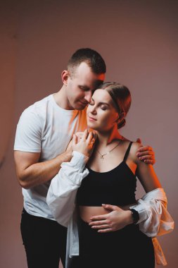 A couple in love in white shirts are hugging and enjoying each other. A stylish couple embraces each other on a white background. Happy family concept