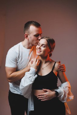 A couple in love in white shirts are hugging and enjoying each other. A stylish couple embraces each other on a white background. Happy family concept