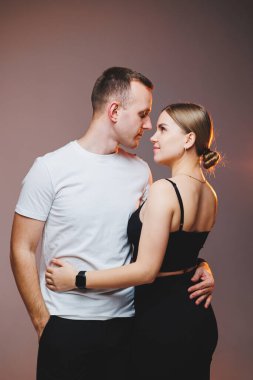 A couple in love in white shirts are hugging and enjoying each other. A stylish couple embraces each other on a white background. Happy family concept