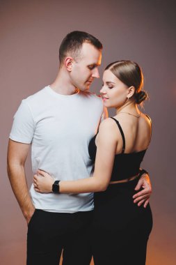 A couple in love in white shirts are hugging and enjoying each other. A stylish couple embraces each other on a white background. Happy family concept
