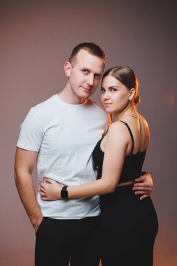 A couple in love in white shirts are hugging and enjoying each other. A stylish couple embraces each other on a white background. Happy family concept