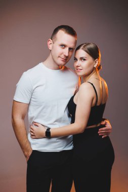 A couple in love in white shirts are hugging and enjoying each other. A stylish couple embraces each other on a white background. Happy family concept