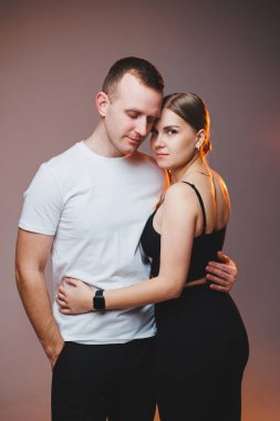A couple in love in white shirts are hugging and enjoying each other. A stylish couple embraces each other on a white background. Happy family concept