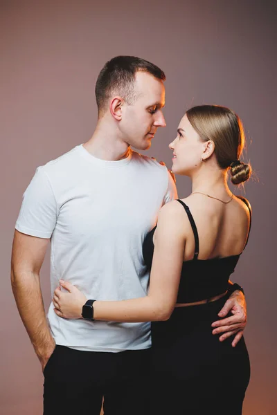 A couple in love in white shirts are hugging and enjoying each other. A stylish couple embraces each other on a white background. Happy family concept
