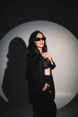 Young elegant stylish woman in a black suit. Studio shot. A woman in a black suit and black glasses on a white background
