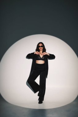 Young elegant stylish woman in a black suit. Studio shot. A woman in a black suit and black glasses on a white background
