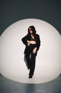 Young elegant stylish woman in a black suit. Studio shot. A woman in a black suit and black glasses on a white background