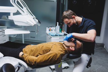 An orthodontist treats the teeth of his patient in a modern, bright office. Orthodontic treatment of teeth.