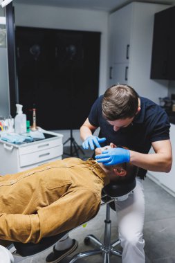 An orthodontist treats the teeth of his patient in a modern, bright office. Orthodontic treatment of teeth.