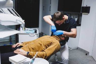 An orthodontist treats the teeth of his patient in a modern, bright office. Orthodontic treatment of teeth.