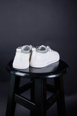 Women's white leather sneakers close-up on a black background. Women's everyday comfortable shoes.