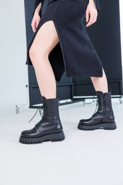 Close-up of female legs in black leather lace-up boots. Women's comfortable spring casual shoes. Black women's spring boots