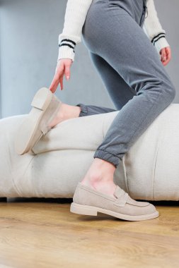 Female legs close-up in gray shoes without heels. Women's comfortable summer casual shoes. Gray women's spring shoes