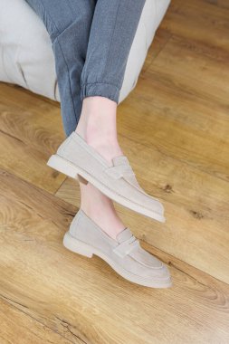 Female legs close-up in gray shoes without heels. Women's comfortable summer casual shoes. Gray women's spring shoes