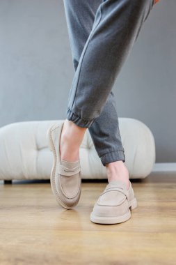 Female legs close-up in gray shoes without heels. Women's comfortable summer casual shoes. Gray women's spring shoes