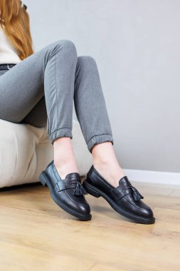 Close-up of female legs in pants and black leather classic shoes. Women's comfortable summer shoes. New spring-summer collection of women's leather shoes 2023