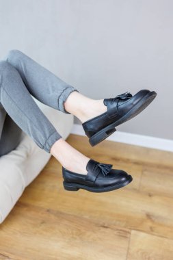 Close-up of female legs in pants and black leather classic shoes. Women's comfortable summer shoes. New spring-summer collection of women's leather shoes 2023