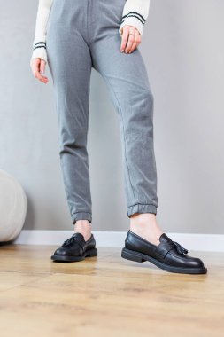 Close-up of female legs in pants and black leather classic shoes. Women's comfortable summer shoes. New spring-summer collection of women's leather shoes 2023