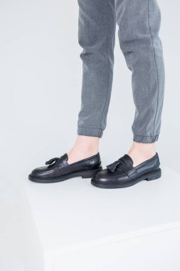 Close-up of female legs in pants and black leather classic shoes. Women's comfortable summer shoes. New spring-summer collection of women's leather shoes 2023
