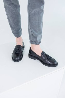 Close-up of female legs in pants and black leather classic shoes. Women's comfortable summer shoes. New spring-summer collection of women's leather shoes 2023