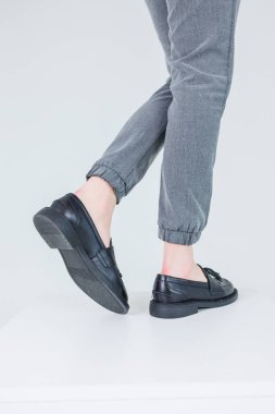 Close-up of female legs in pants and black leather classic shoes. Women's comfortable summer shoes. New spring-summer collection of women's leather shoes 2023