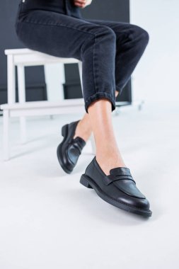 Close-up of female legs in pants and black leather classic chelsea shoes. Women's comfortable summer shoes. New spring-summer collection of women's leather shoes 2023