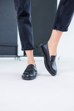 Close-up of female legs in pants and black leather classic chelsea shoes. Women's comfortable summer shoes. New spring-summer collection of women's leather shoes 2023