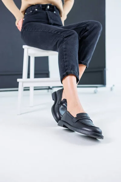 Close-up of female legs in pants and black leather classic chelsea shoes. Women\'s comfortable summer shoes. New spring-summer collection of women\'s leather shoes 2023