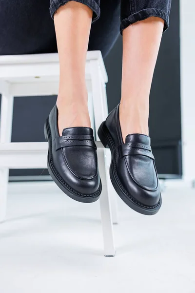 Close-up of female legs in pants and black leather classic chelsea shoes. Women\'s comfortable summer shoes. New spring-summer collection of women\'s leather shoes 2023