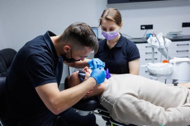 Asistanı olan bir ortodontist dişlerini diş aletleriyle tedavi eder. Diş hekimliği. Dişlerin ortodonti tedavisi