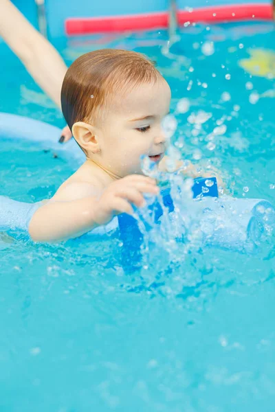 A 2-year-old little boy learns to swim in a pool with a coach. Swimming lessons for children