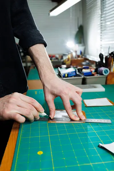 stock image A man's hand holds pieces of leather for a leather wallet in his workshop. The process of working with natural brown leather. The craftsman holds the craft