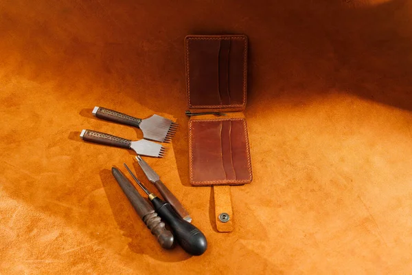 Production of handicrafts from genuine leather. Tools for making leather goods and pieces of brown leather. Production of leather products. View from above