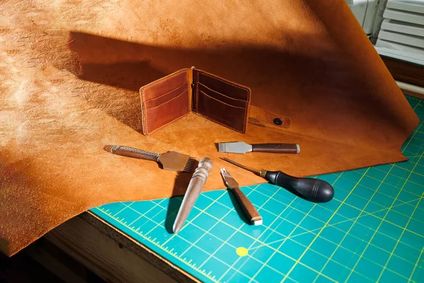 Production of handicrafts from genuine leather. Tools for making leather goods and pieces of brown leather. Production of leather products. View from above