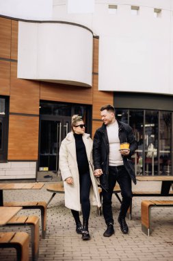 Sonbaharda birbirine aşık genç bir çift sokakta yürüyor ve kahve içiyor. Açık havada eğlenmek için. Genç şık bir çift..