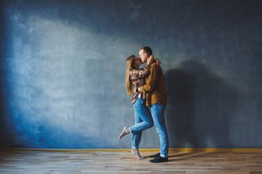 Happy couple in love dressed in shirts, standing on the background of gray wall, looking at empty space, isolated background of gray concrete wall. The concept of a happy couple in love.