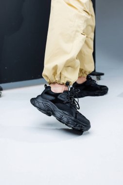 Sıradan kadın modası. Kadınlar için rahat ayakkabılar. Pantolon giymiş ince kadın bacakları ve siyah şık spor ayakkabıları. Kadınların rahat yaz ayakkabıları..