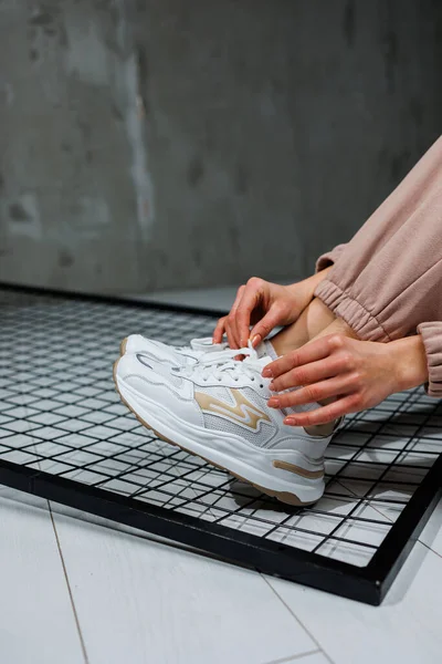 Sports shoes for women. Slender female legs in pants and white stylish casual sneakers. Women's comfortable summer shoes.