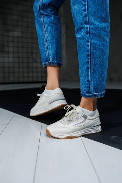 Sports shoes for women. Slender female legs in jeans and white stylish casual sneakers. Women\'s comfortable summer shoes. Casual women\'s fashion