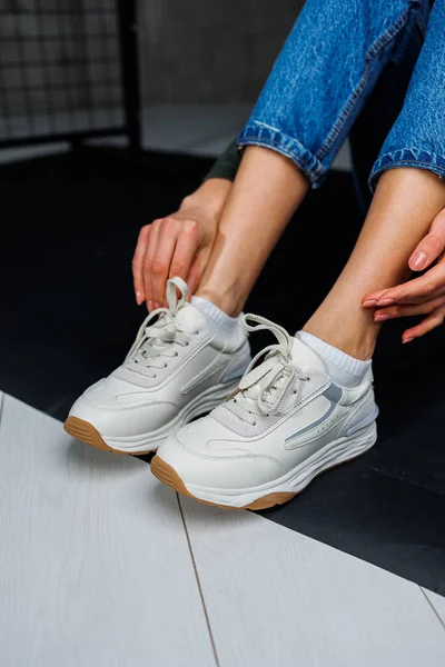 Sports shoes for women. Slender female legs in jeans and white stylish casual sneakers. Women\'s comfortable summer shoes. Casual women\'s fashion
