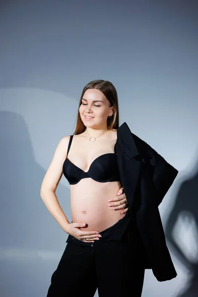 上品な妊婦さん 黒のスーツに長い髪の美しい妊娠中の女の子は灰色の背景に 幸せな妊娠と家族の概念 — ストック写真