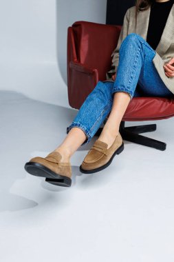 Sıradan kadın modası. Kadınlar için klasik ayakkabılar. Pantolon içinde ince kadın bacakları ve kahverengi stil mokasen ayakkabılar. Kadınların rahat yaz ayakkabıları..