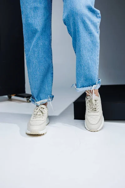 Κοντινό Πλάνο Γυναικείων Ποδιών Τζιν Και Λευκά Stylish Sneakers Γυναικεία — Φωτογραφία Αρχείου