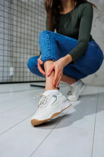 Casual women\'s fashion. Sports shoes for women. Slender female legs in jeans and white stylish casual sneakers. Women\'s comfortable summer shoes.