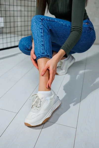 Casual women's fashion. Sports shoes for women. Slender female legs in jeans and white stylish casual sneakers. Women's comfortable summer shoes.