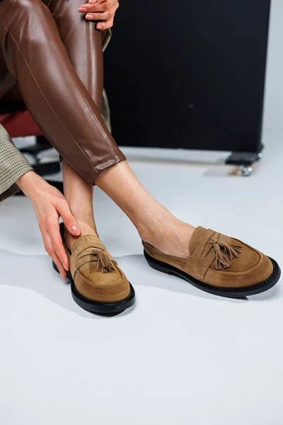 Casual women's fashion. Classic shoes for women. Slender female legs in trousers and brown stylish casual loafers. Women's comfortable summer shoes.