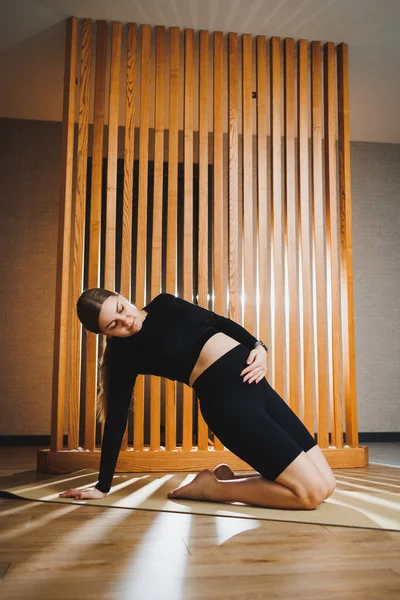 stock image Pregnant woman doing sports on mat at home. Young pregnant woman doing stretching and yoga at home. Activity during pregnancy