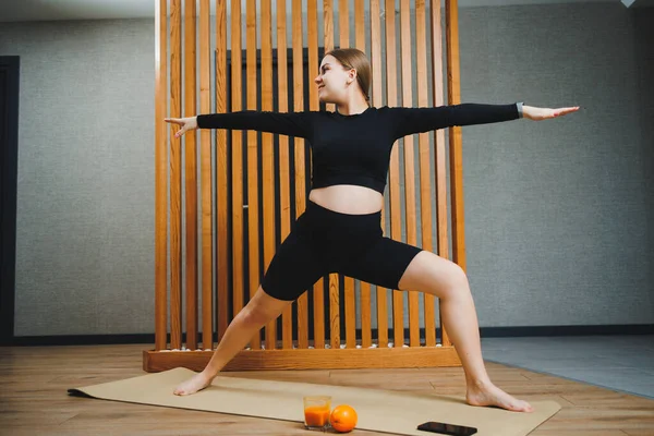 stock image Pregnant woman doing sports on mat at home. Young pregnant woman doing stretching and yoga at home. Activity during pregnancy