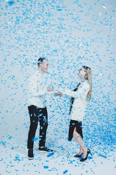 stock image Young happy married couple hugging in blue confetti. A couple in love rejoices and has fun. Gender photo session